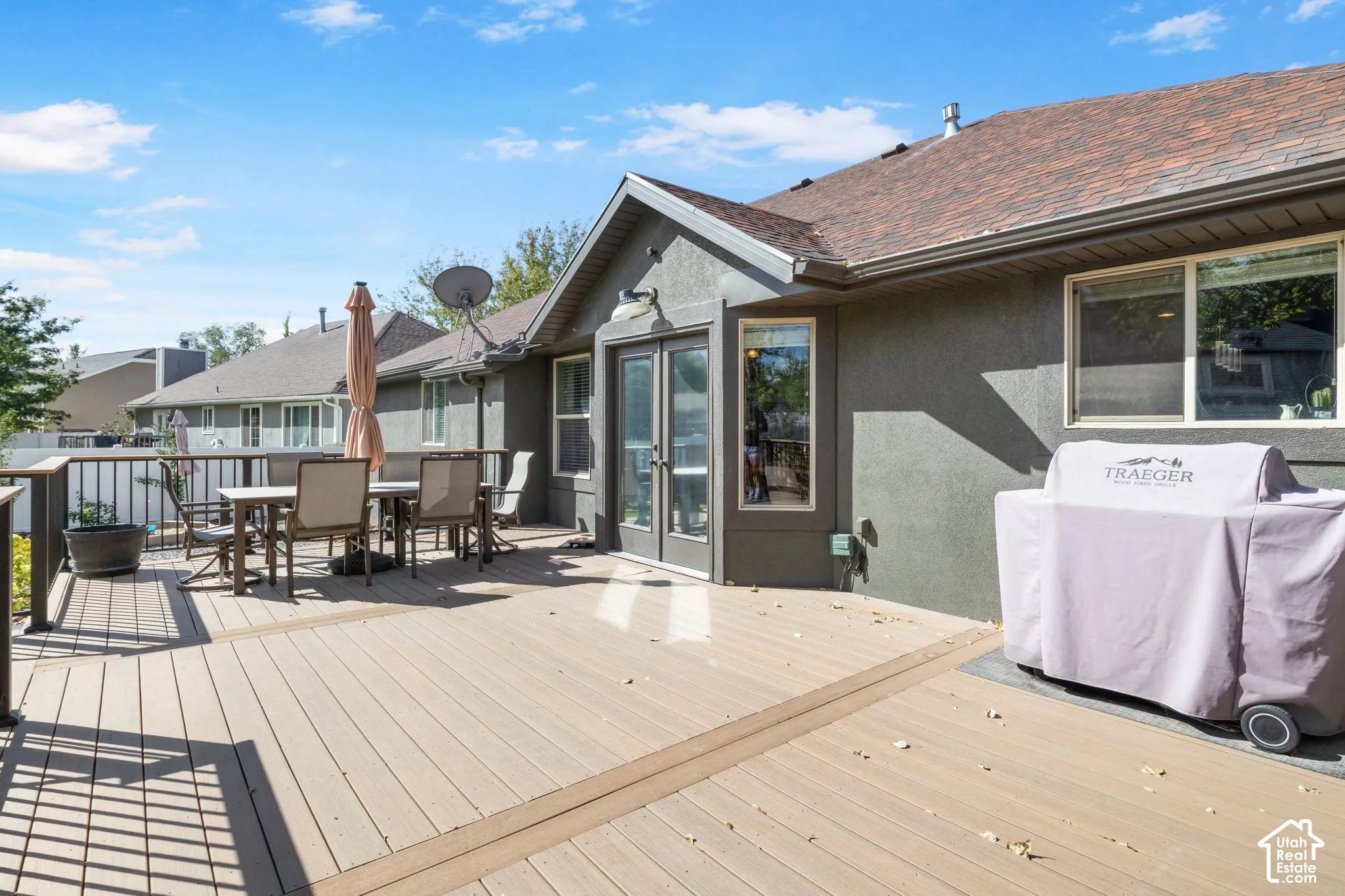 Expansive outdoor deck with a composite surface and dark railing, featuring a stucco exterior
