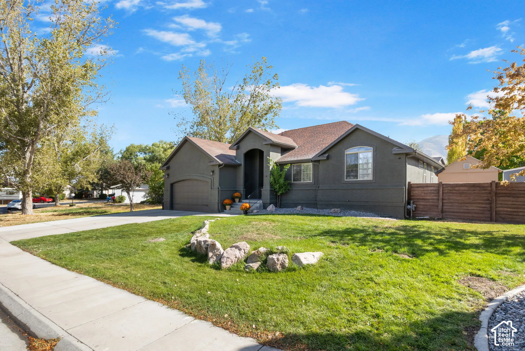 Single-story exterior with a two-car garage, mature landscaping, and a privacy fence