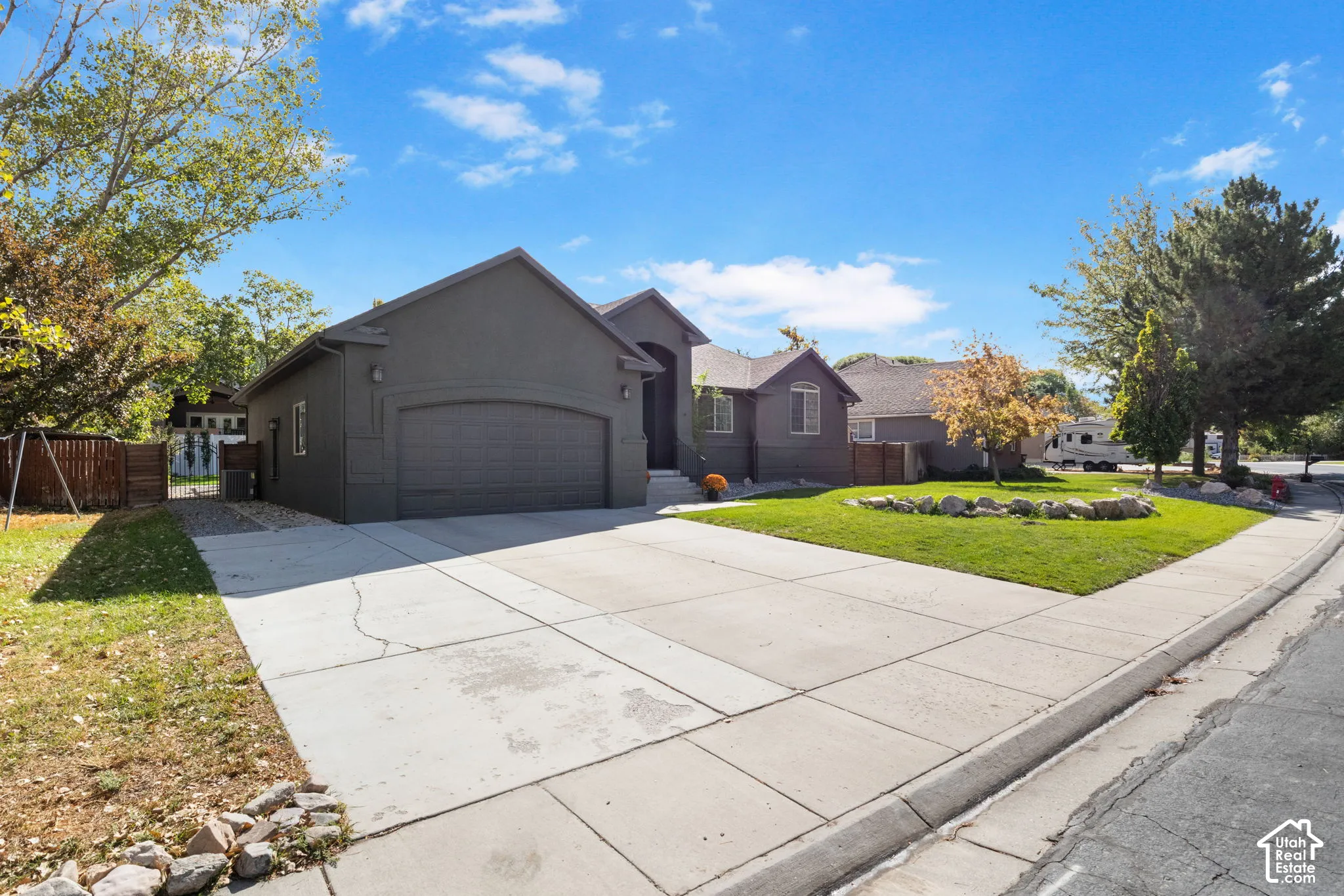 Contemporary single-story exterior with an attached garage, featuring a concrete driveway and sidewalk