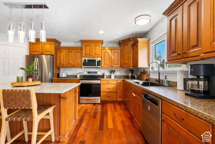 Kitchen featuring wood-finish flooring, wood cabinetry, stone countertops, and stainless steel appliances