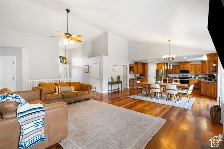 Vaulted ceilings with a ceiling fan, wood-finish flooring, recessed lighting, and a kitchen with wood cabinetry and stainless steel appliances