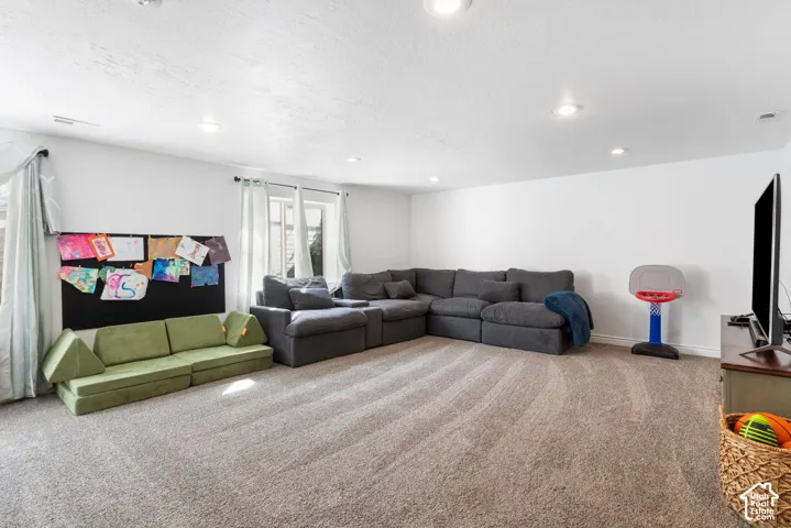 Carpeted floor, recessed lighting, and multiple windows with curtain rods