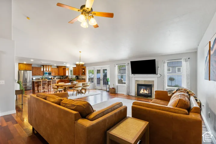 Spacious living area featuring vaulted ceilings, wood-finish flooring, a gas fireplace with a mantel, and double french doors