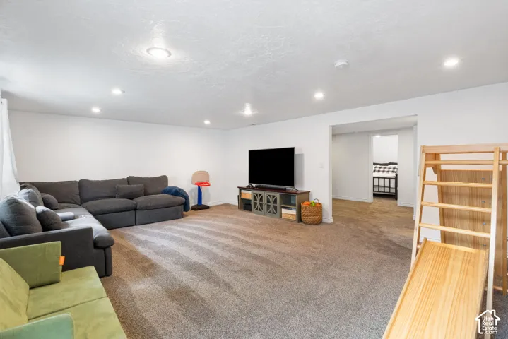 Recessed ceiling lighting, carpeted flooring, white painted walls, and an open entryway