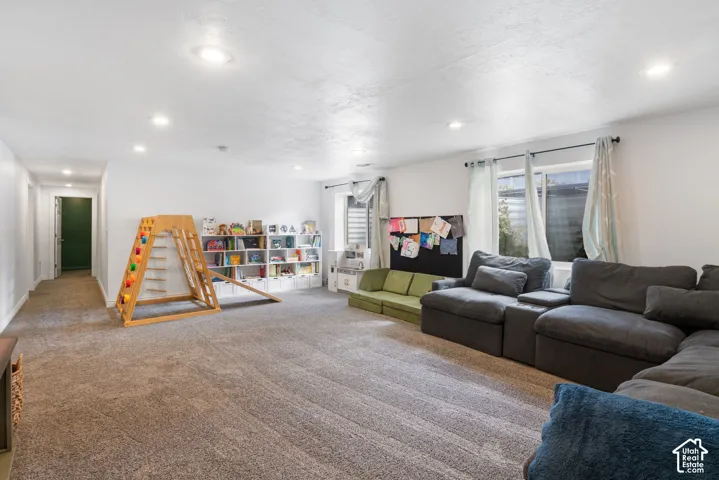 Recessed lighting illuminates the carpeted flooring and white walls