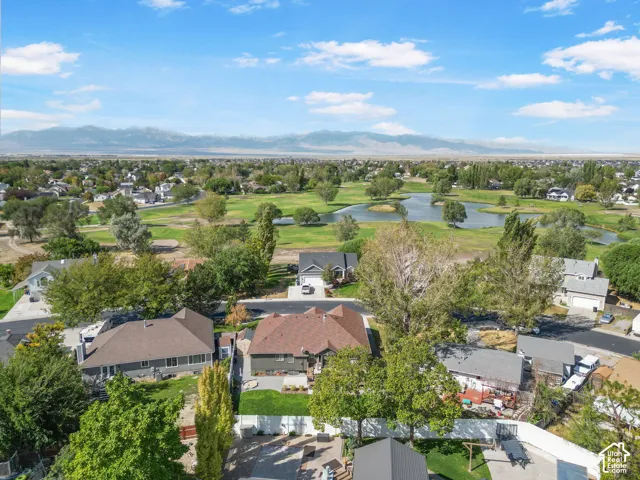 Residential neighborhood with extensive green spaces, a prominent pond, and distant mountains
