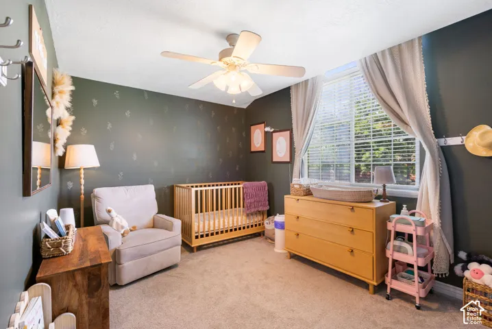 Carpeted room with a ceiling fan, a window with blinds, and decorative wall accents