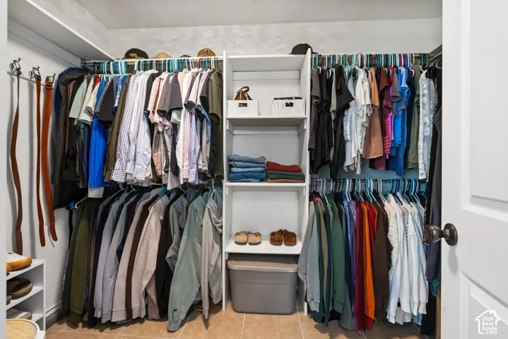 Walk-in closet featuring built-in shelving, multiple hanging rods, and tile flooring