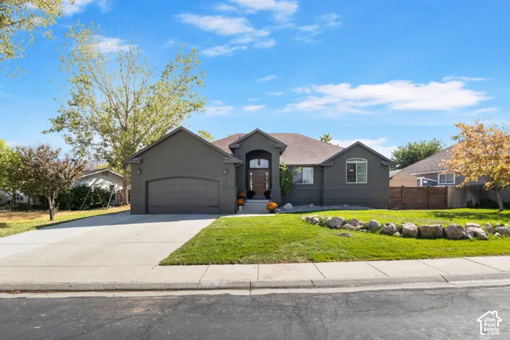 Contemporary stucco exterior with an arched entryway, attached garage, concrete driveway, and a front lawn with rock landscaping