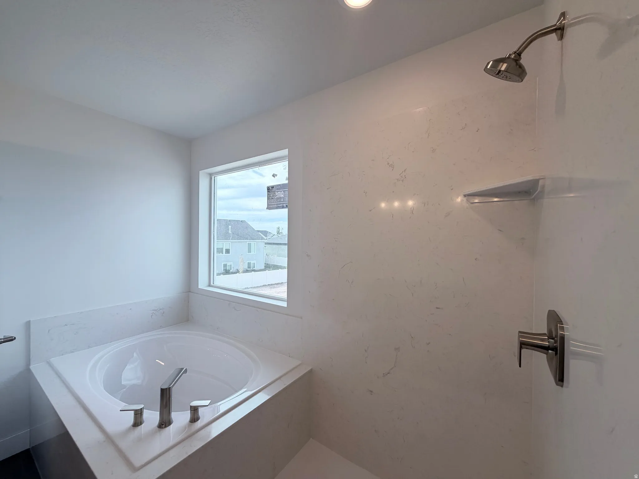 Recessed lighting, built-in soaking tub, brushed nickel fixtures, window, and shower with integrated shelf