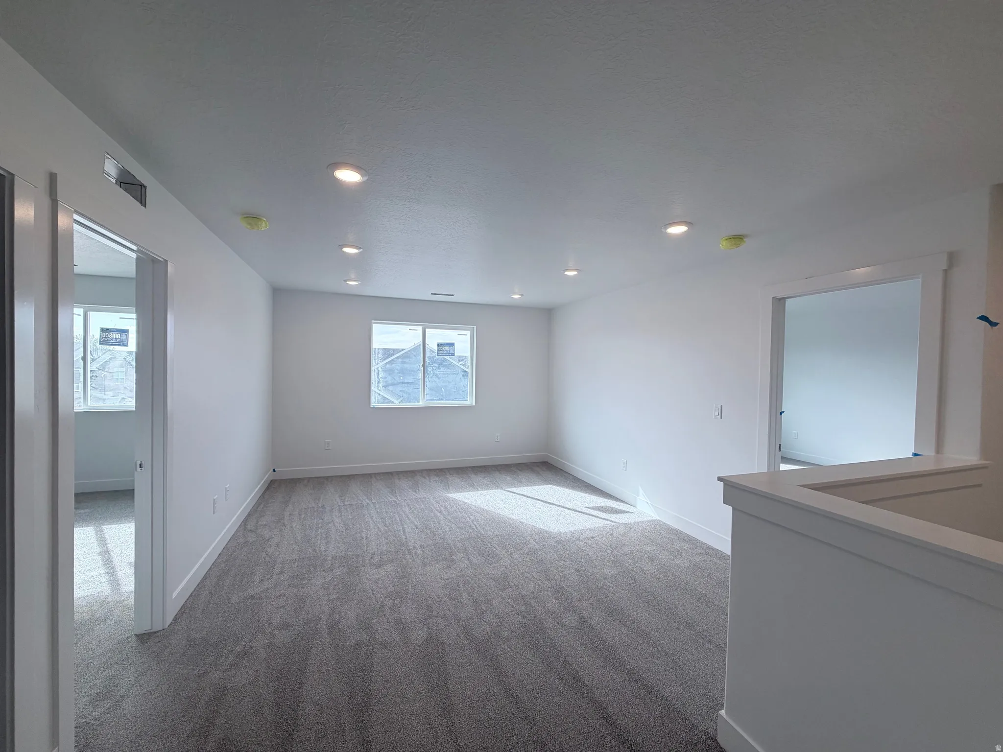 Recessed ceiling lighting, white painted walls, gray carpet, multiple windows, and white trim