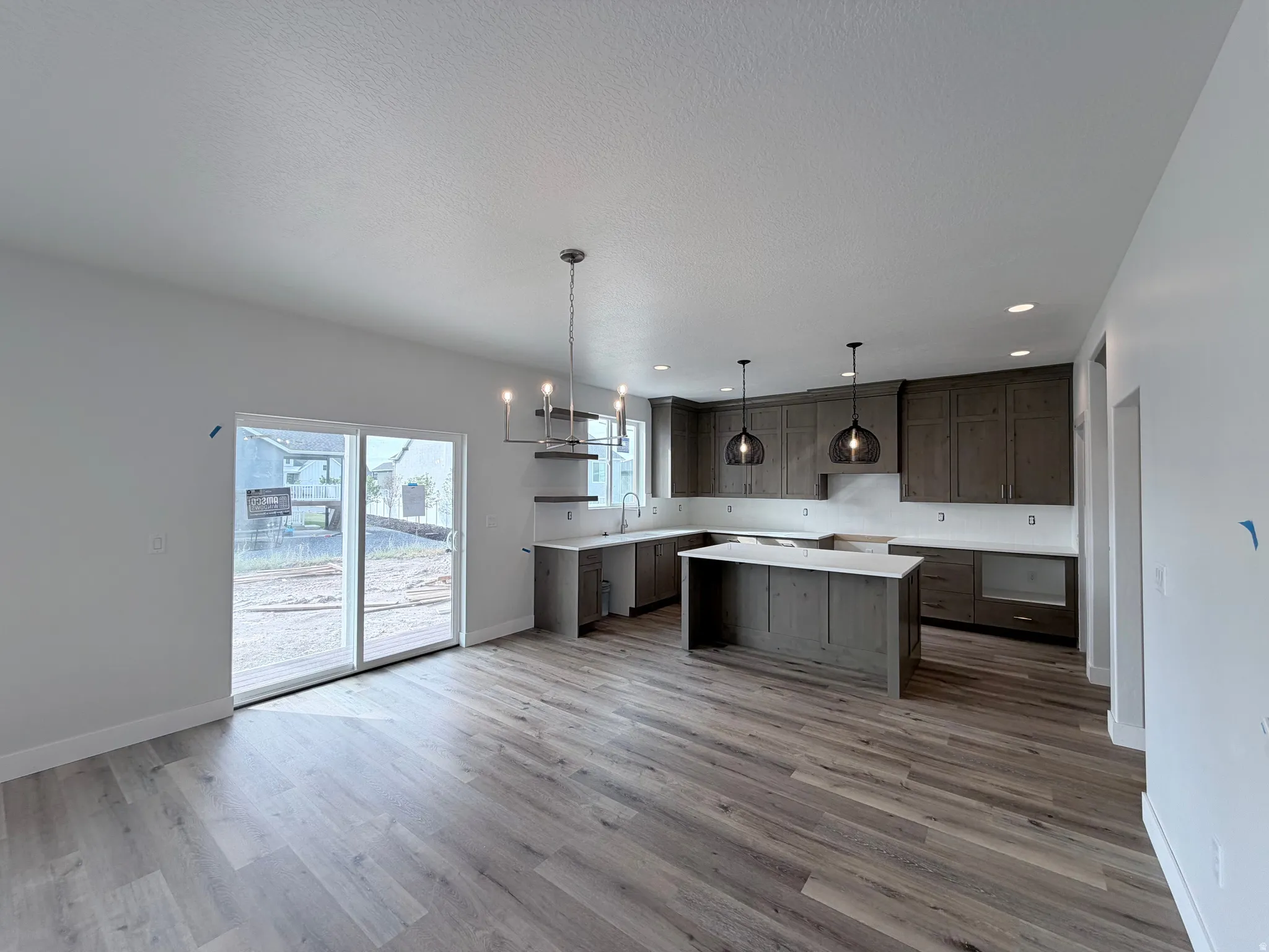 Spacious kitchen featuring dark wood-finish cabinetry, light-toned countertops, and an island with seating