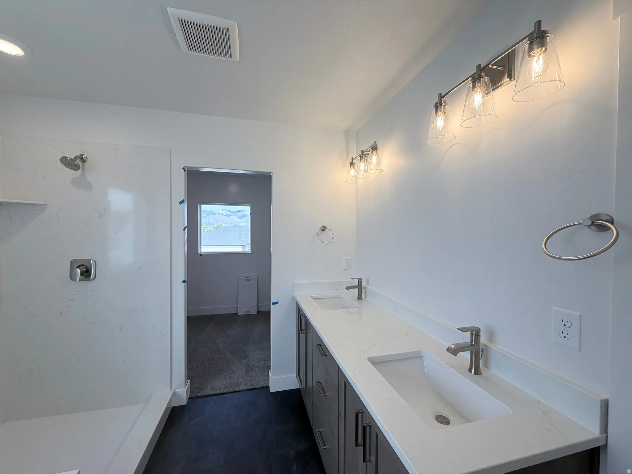 Dual vanity with integrated sinks and brushed nickel faucets, quartz countertops, and dark wood-finish cabinetry