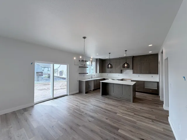 Spacious kitchen featuring dark wood-finish cabinetry, light-toned countertops, and an island with seating