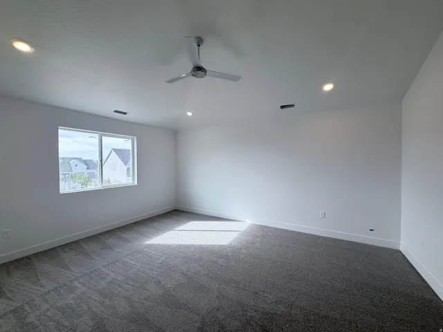 Recessed ceiling lighting, modern ceiling fan, white walls, gray carpet, and a large window