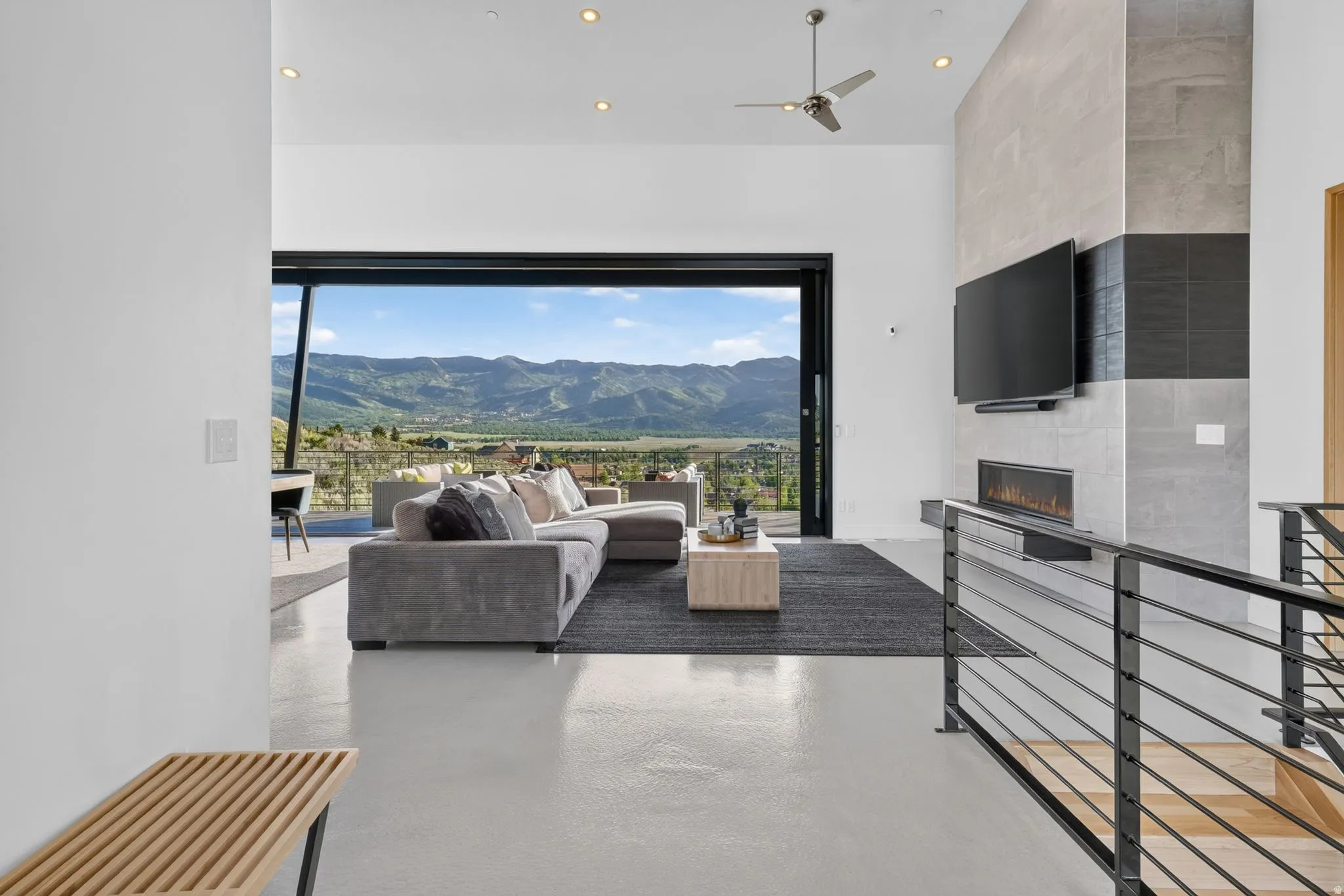 Open concept living space featuring a high ceiling with recessed lighting, a linear fireplace, and a large sliding glass door