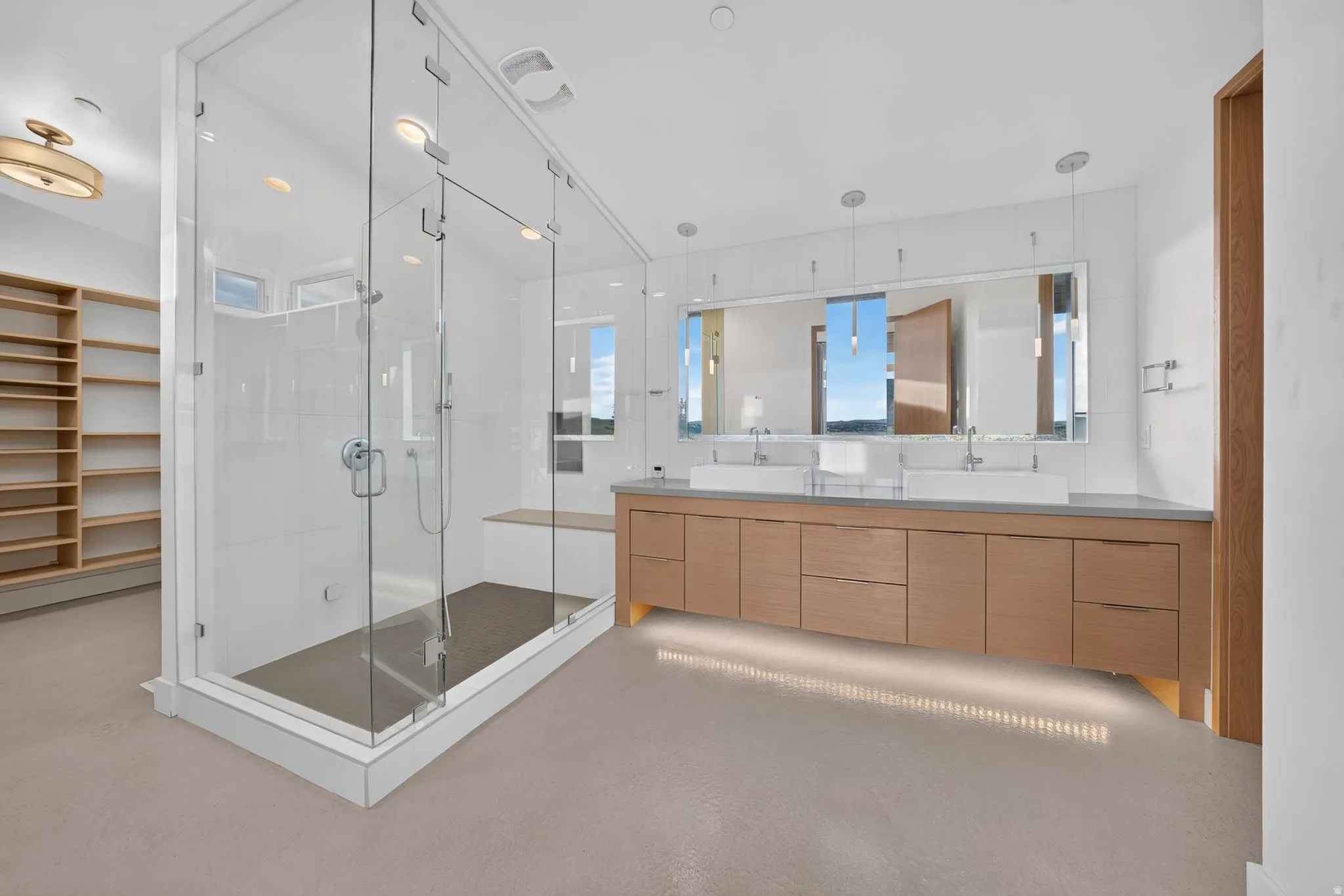 Spacious bathroom featuring a glass-enclosed shower, dual vessel sinks, extensive wood-finish cabinetry, and built-in shelving