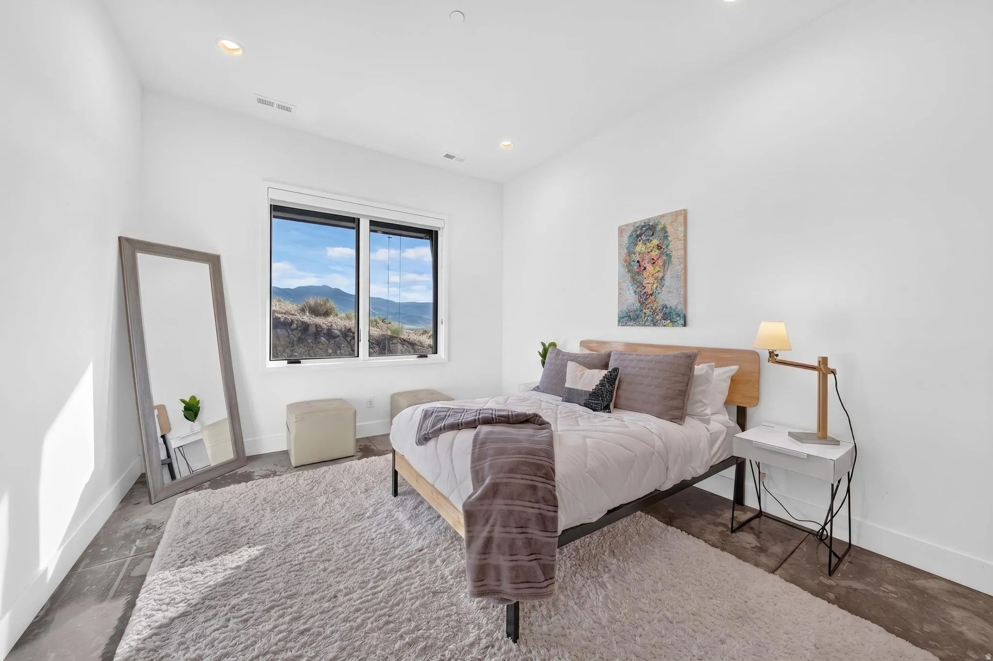 Recessed lighting illuminates a room featuring a large window, a wood-finish headboard, and polished concrete flooring