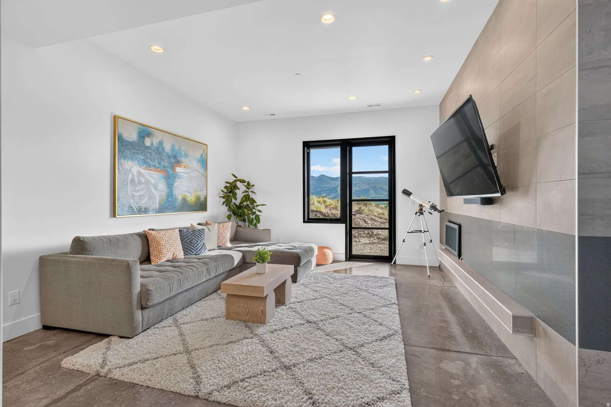 Recessed lighting, concrete flooring, black-framed window, built-in fireplace, and a tiled accent wall