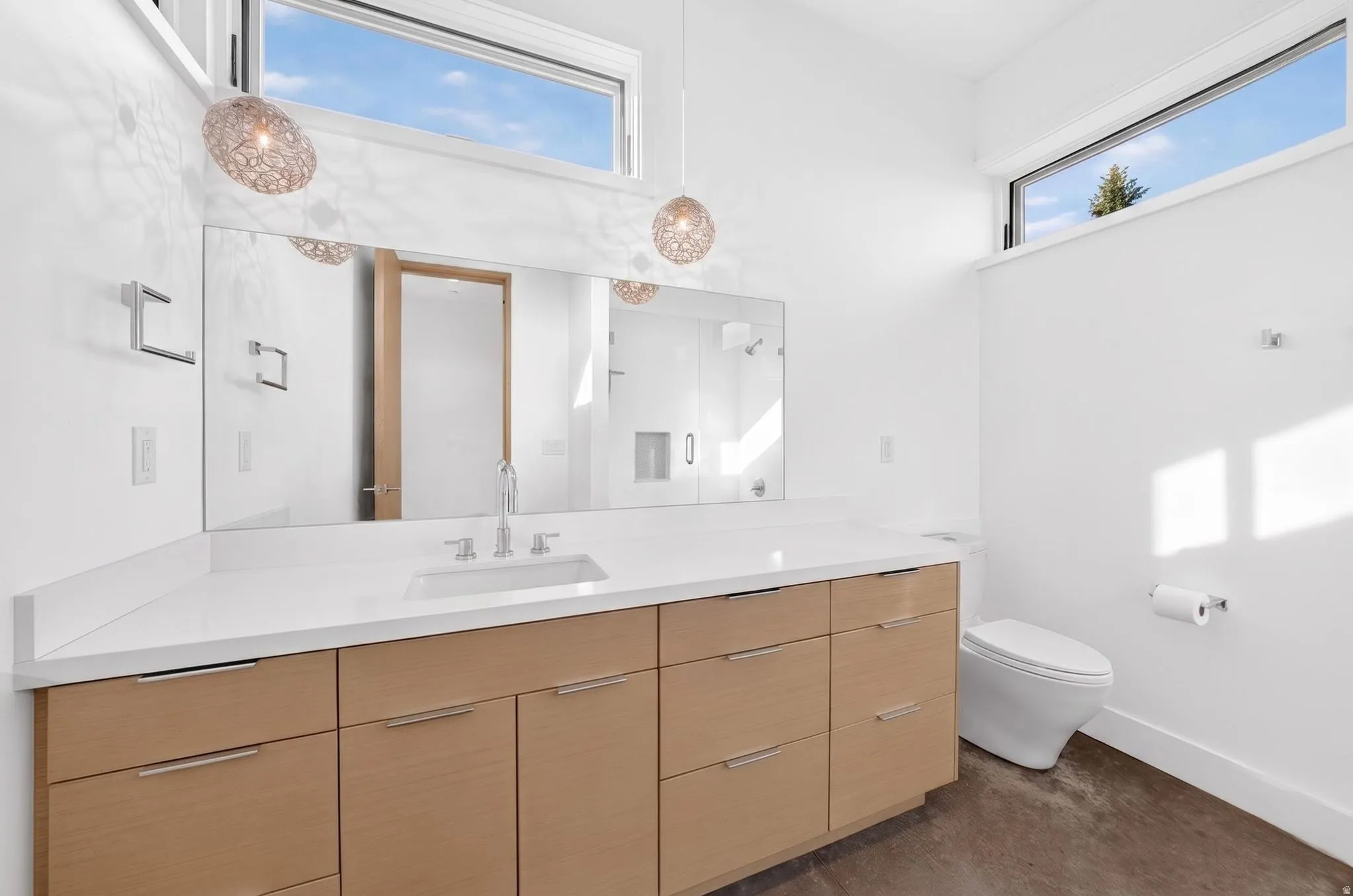 Floating wood-finish vanity with an integrated sink, polished chrome fixtures, and a large wall-mounted mirror