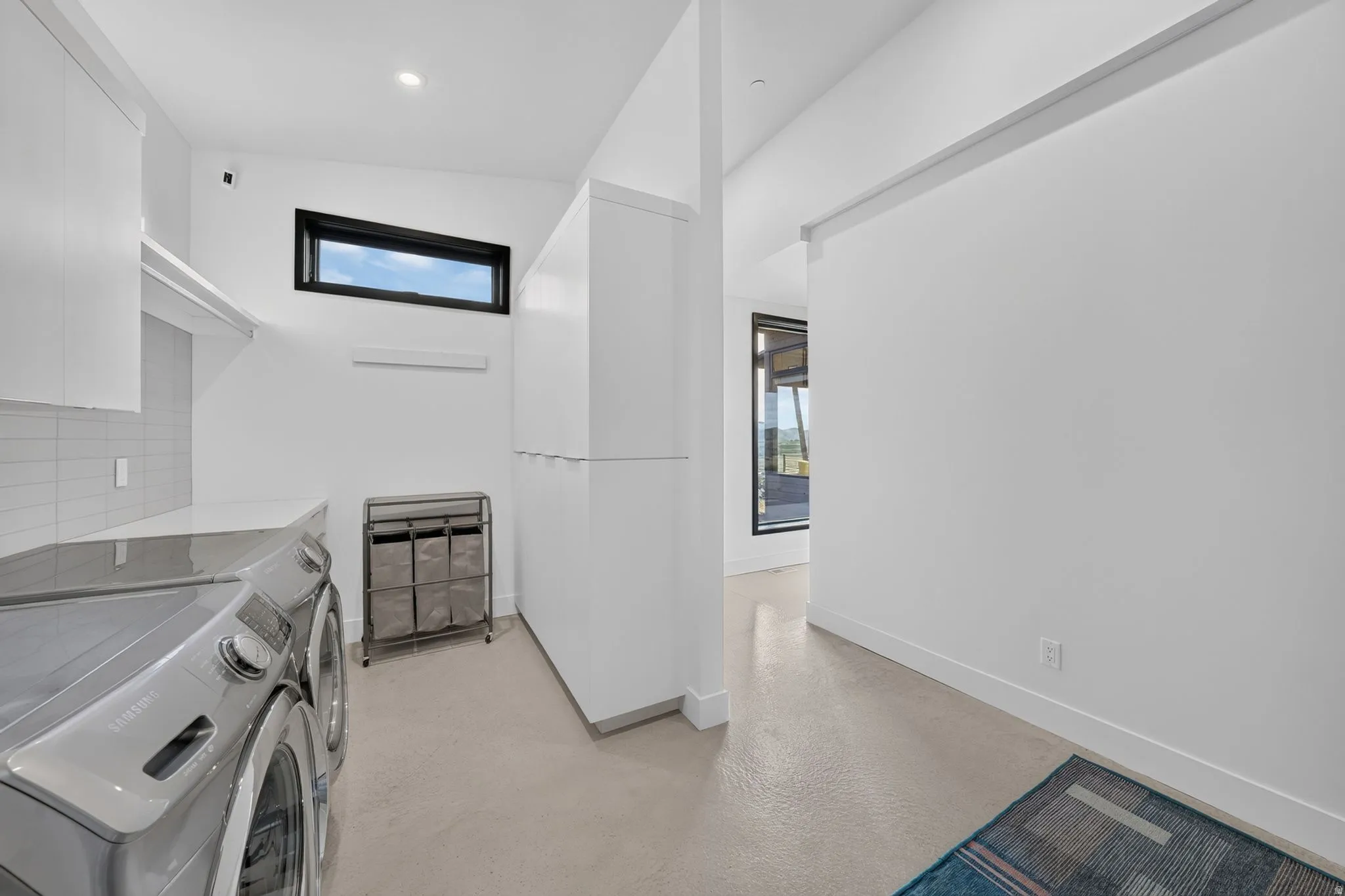 Integrated laundry area featuring upper cabinetry, a counter surface, and a horizontal window