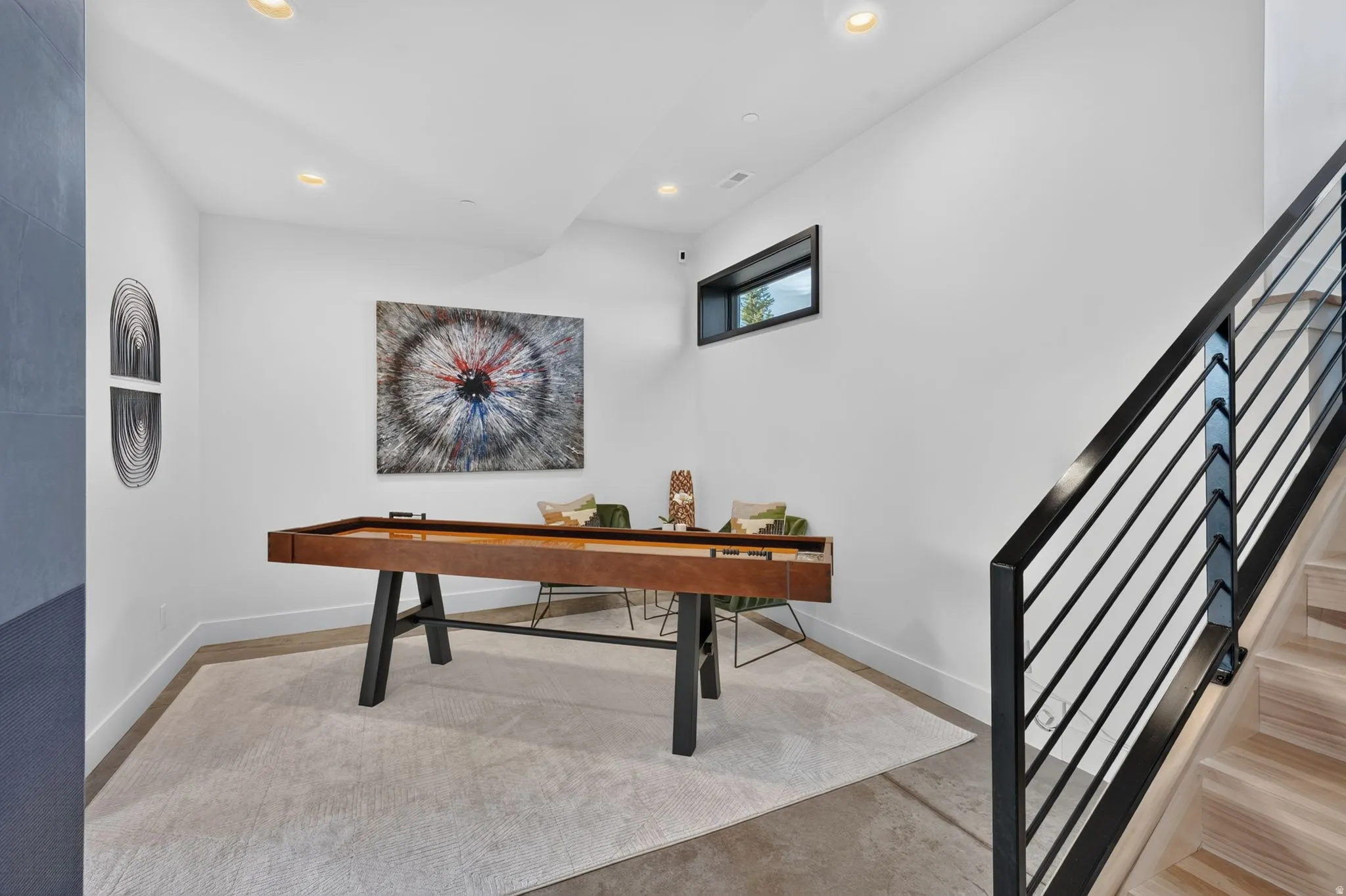 Recessed lighting, wood-finish stairs, and a black metal horizontal bar railing