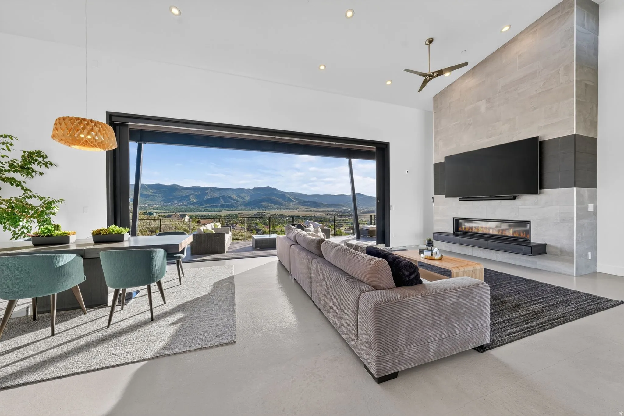 Spacious living area featuring large sliding glass doors, a linear fireplace, a floor-to-ceiling accent wall, and recessed lighting