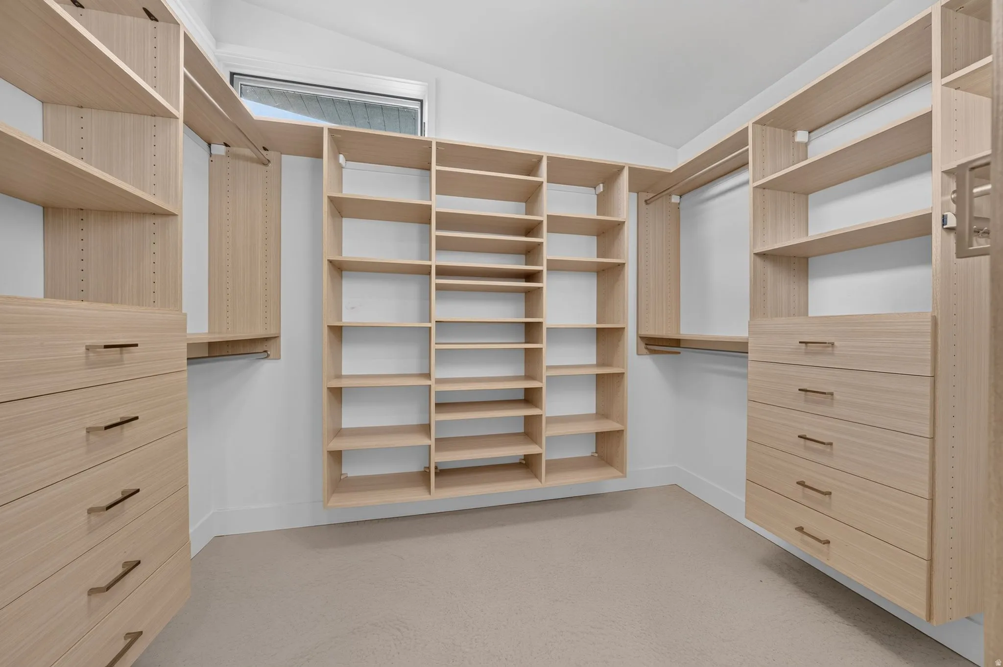 Custom closet system featuring light wood-finish shelving, built-in drawers with modern hardware, and multiple hanging rods