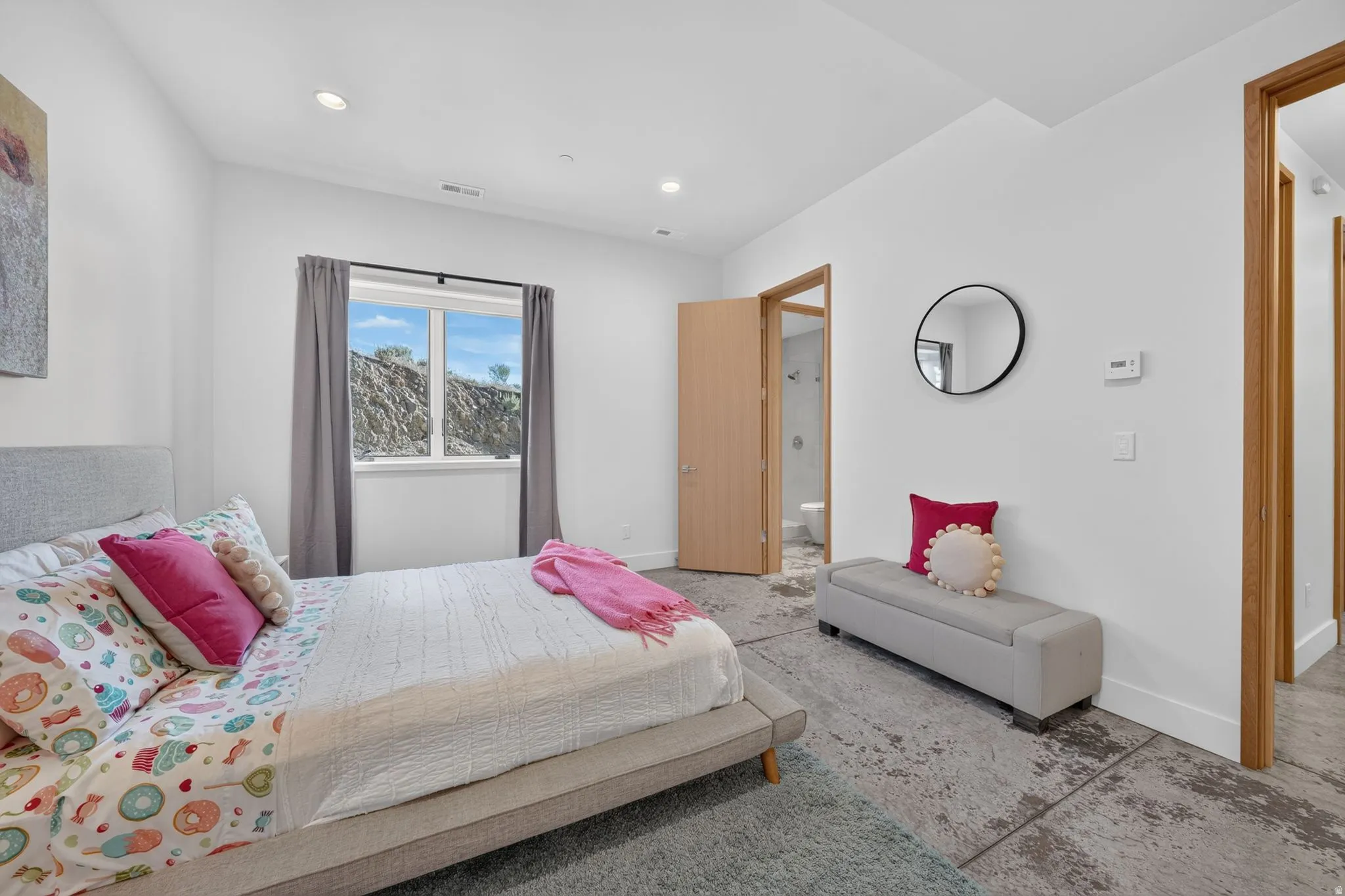White walls, light wood-tone door frames, recessed lighting, and exposed aggregate flooring