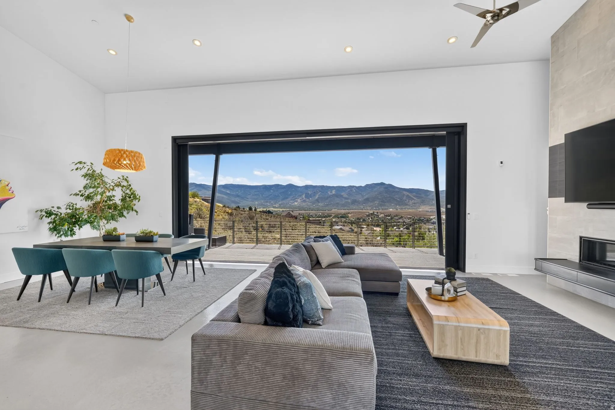 Expansive sliding glass doors, high ceilings, recessed lighting, and a built-in media console with a linear fireplace