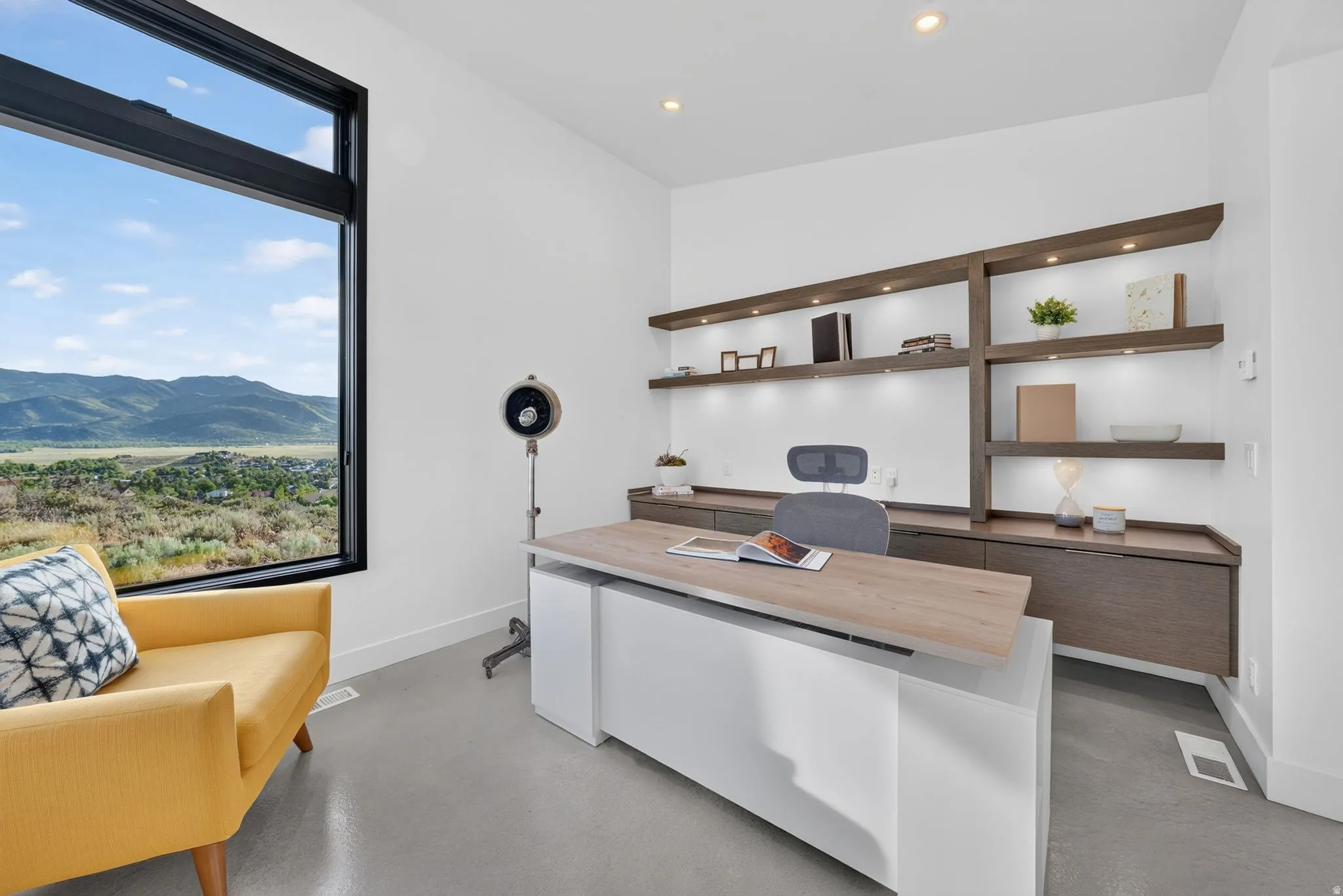 Large format window, built-in shelving with integrated lighting, recessed ceiling lighting, built-in desk unit with wood-finish top