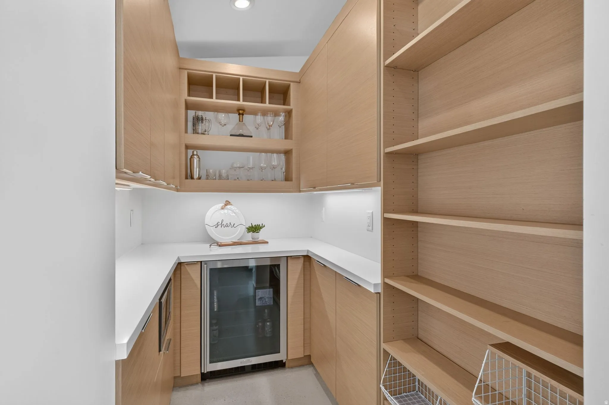 Built-in cabinetry with wood-finish doors, glass-front display shelving, stone countertops, and an integrated beverage refrigerator