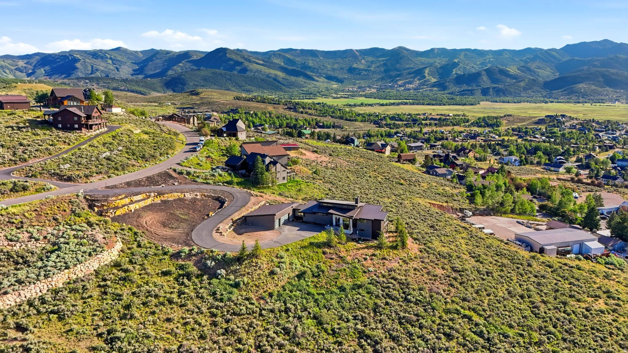 Mountainous backdrop with expansive elevated terrain, featuring a paved winding road
