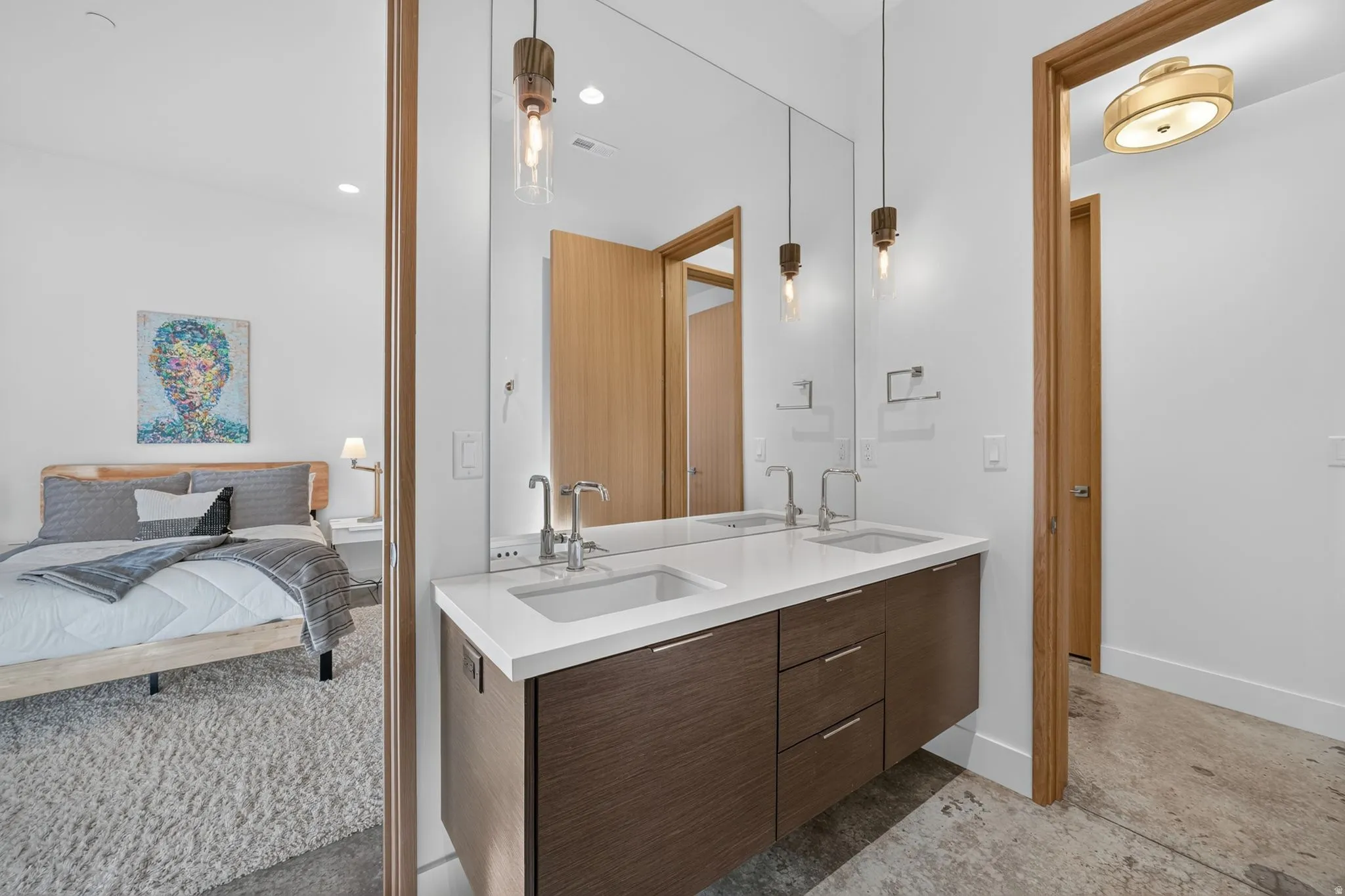 Double vanity with a white countertop and integrated sinks, wood-finish cabinetry, and contemporary pendant lighting