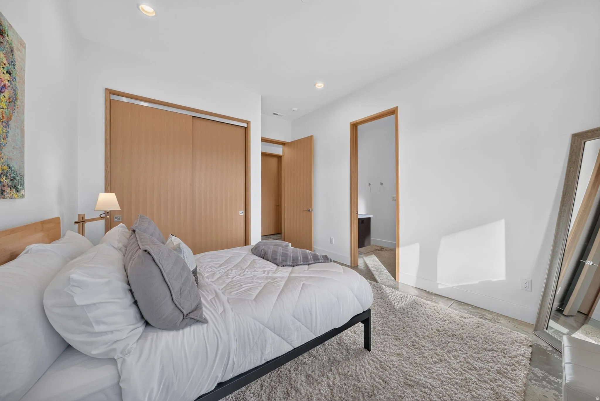 Recessed lighting illuminates the space, featuring wood-finish sliding closet doors and a wood-frame doorway