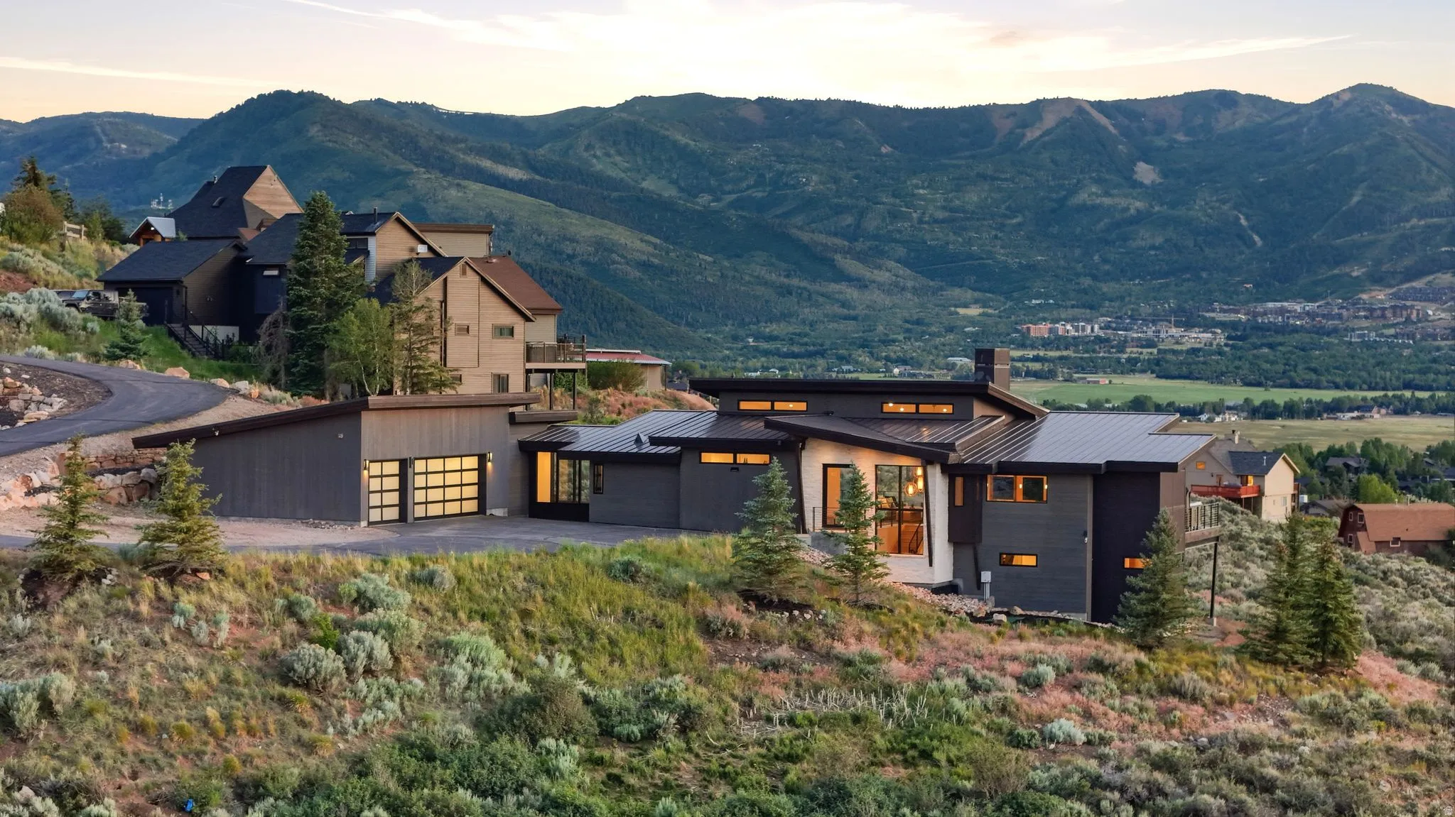 Contemporary architectural design featuring a sloped roofline, attached garage with translucent doors, and expansive windows