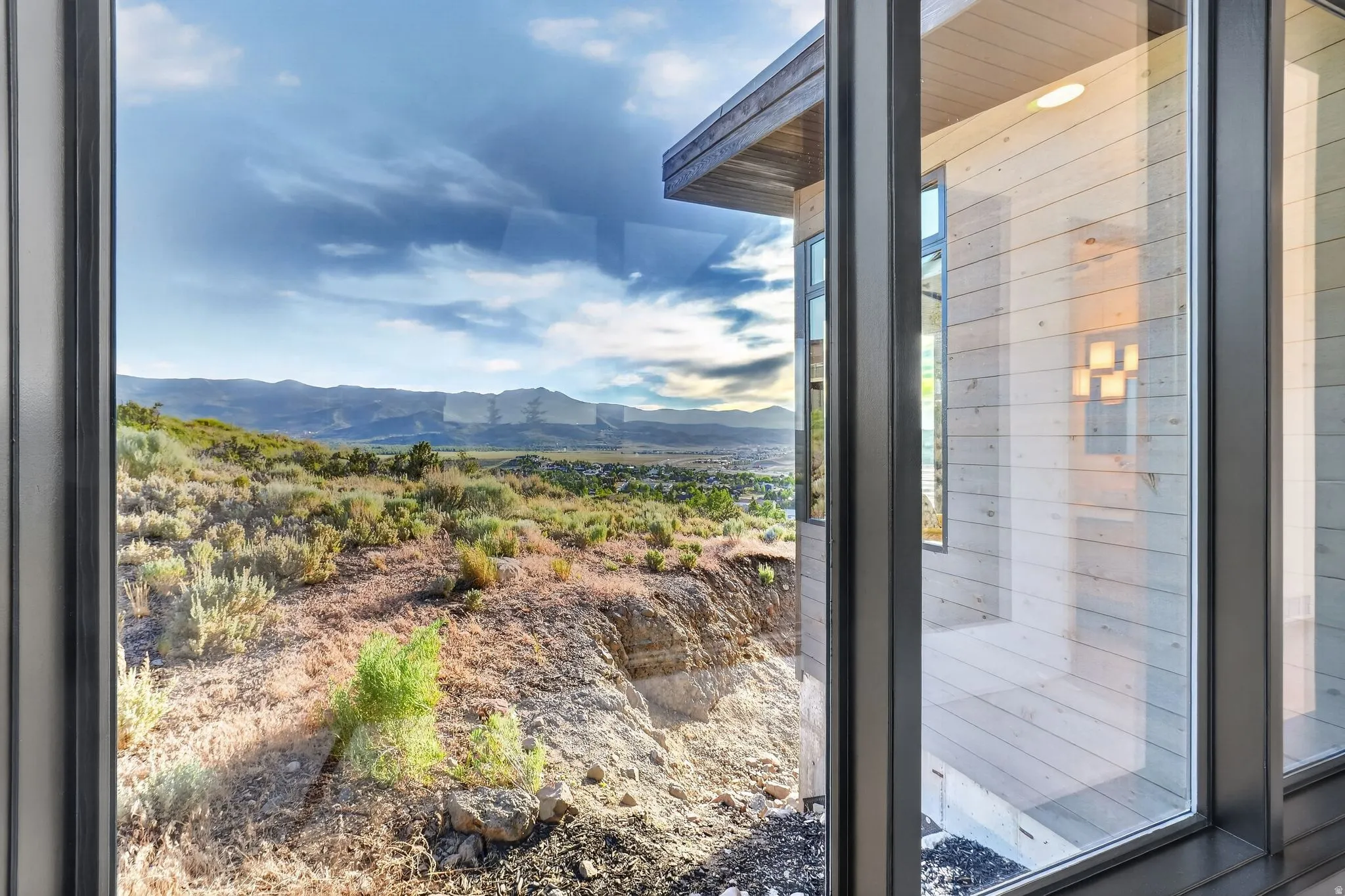 Expansive landscape with distant mountains, exterior horizontal wood siding, modern wall sconce, and recessed ceiling light