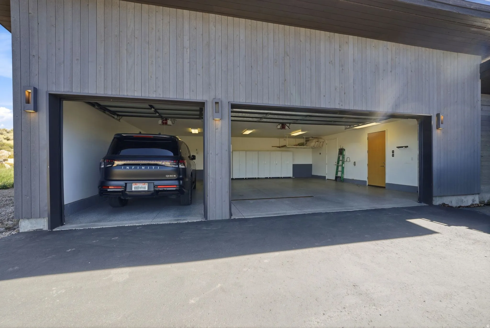 Two-car garage with modern wood-finish siding, integrated wall sconces, and built-in storage cabinetry