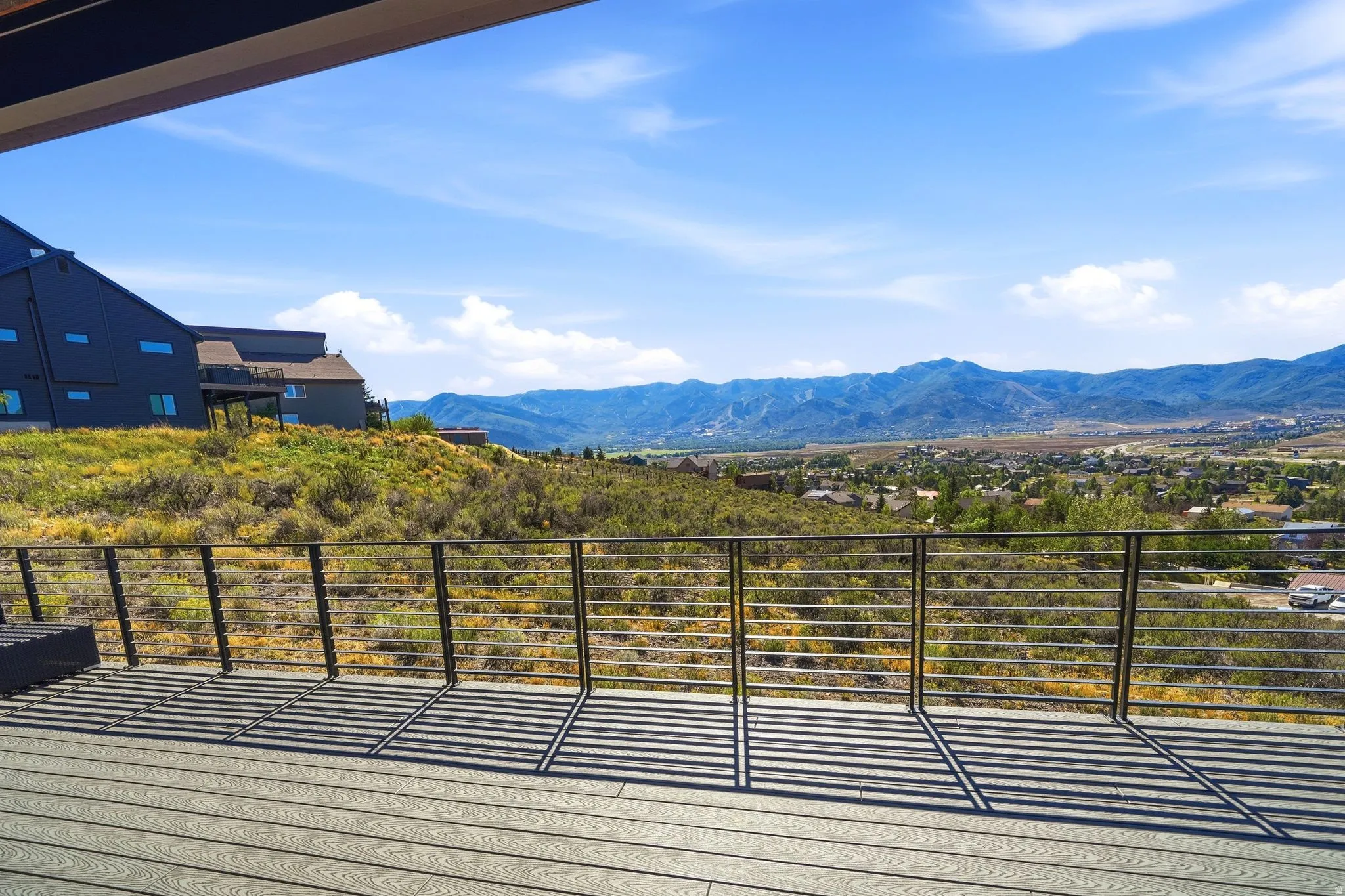 Expansive outdoor deck with composite decking and cable railing, offering a distant mountain landscape and surrounding natural terrain