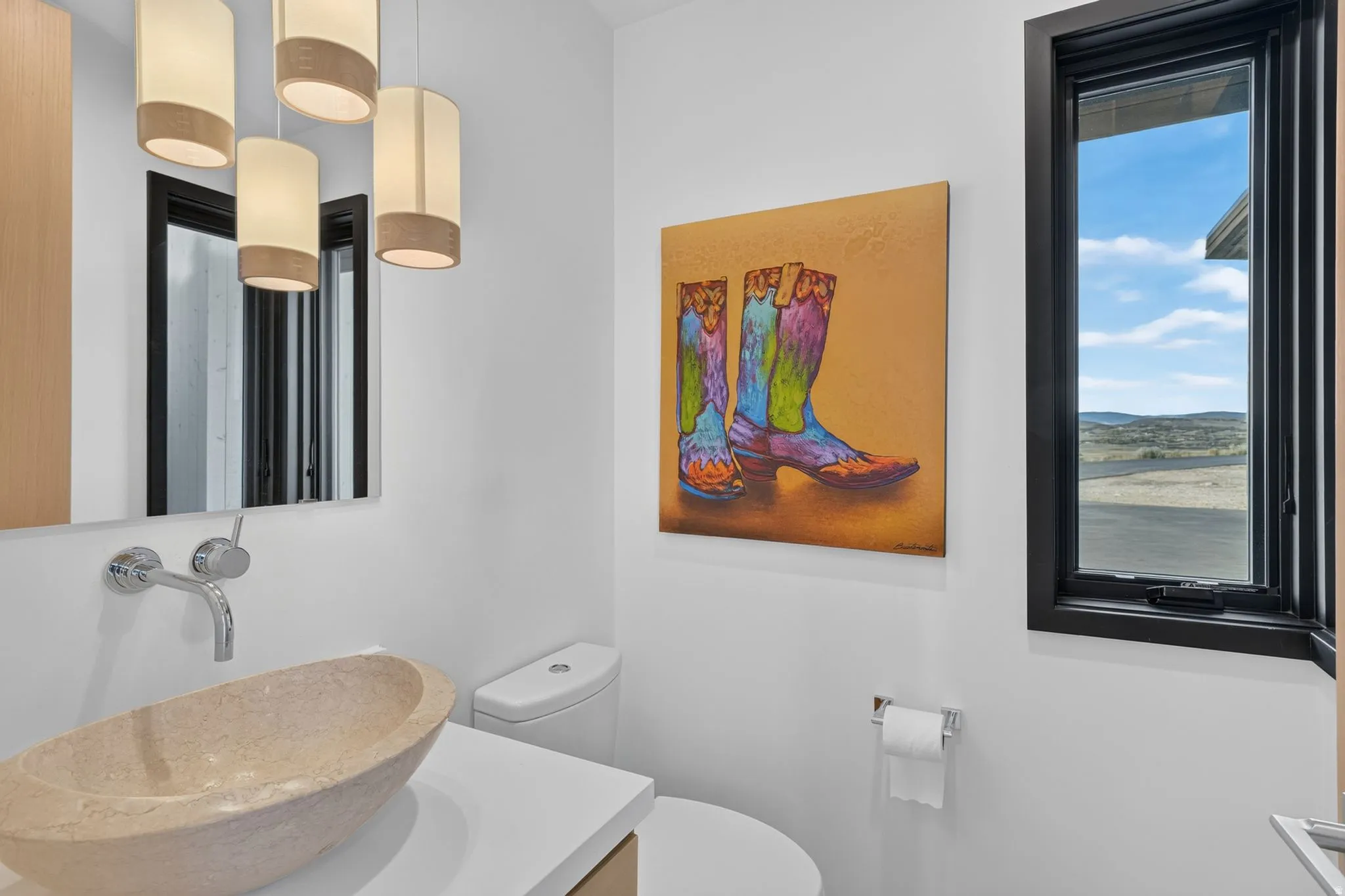 Stone vessel sink with wall-mounted faucet, complemented by a white countertop and natural wood-finish cabinetry