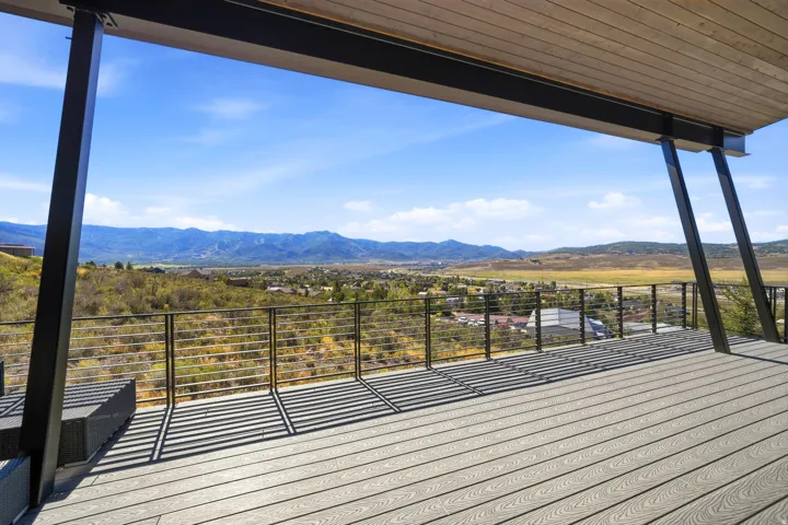 Expansive outdoor deck featuring wood-finish decking, a metal railing system, and structural support beams, all beneath a wood-paneled ceiling