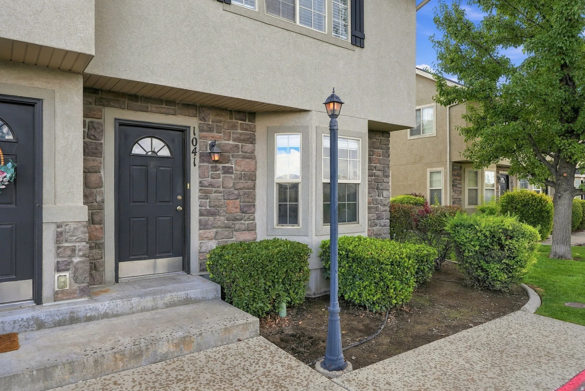 Stucco exterior featuring stone accents, a bay window, and a dark paneled entry door with an arched light
