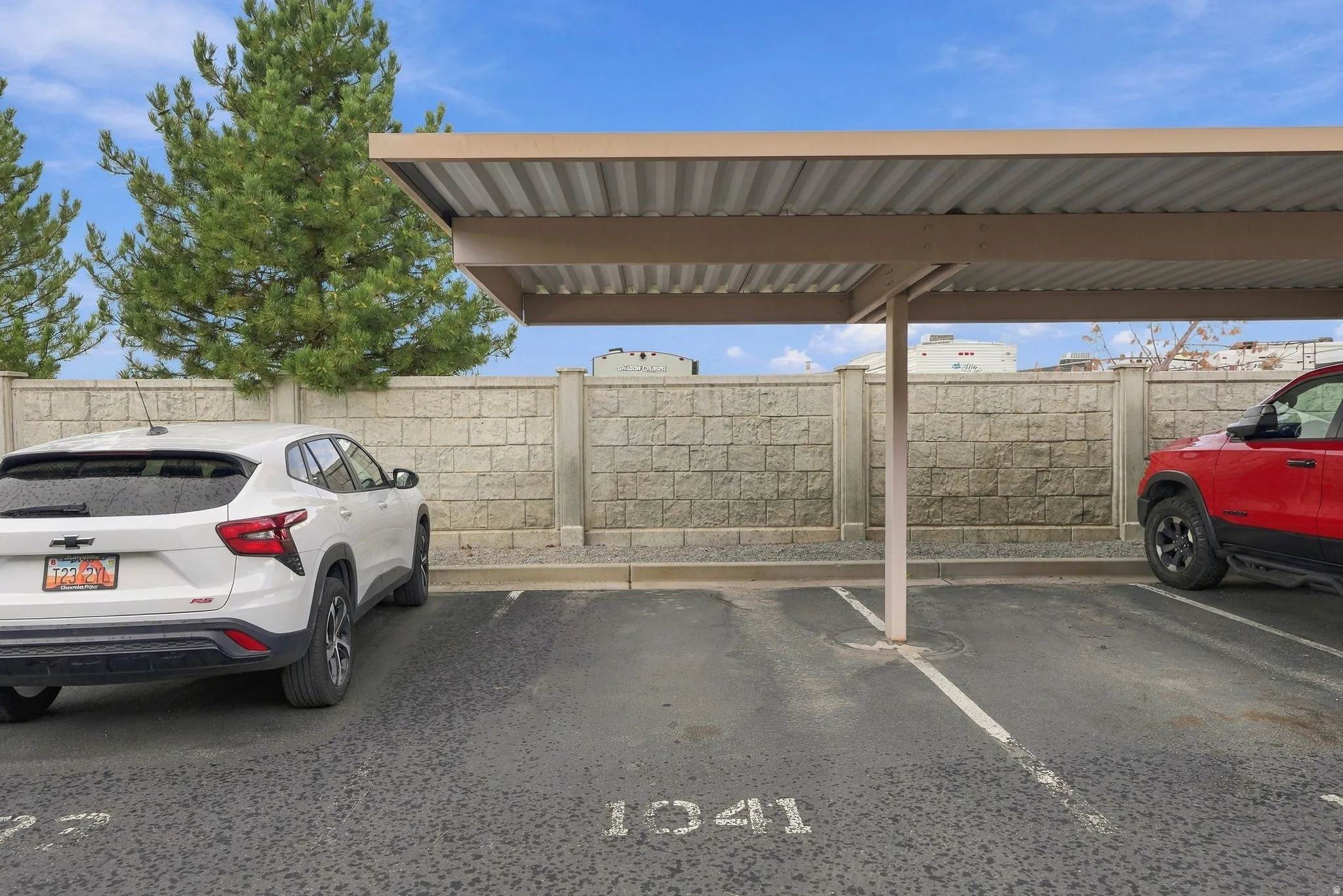 Covered parking space with a corrugated metal roof and a block privacy wall