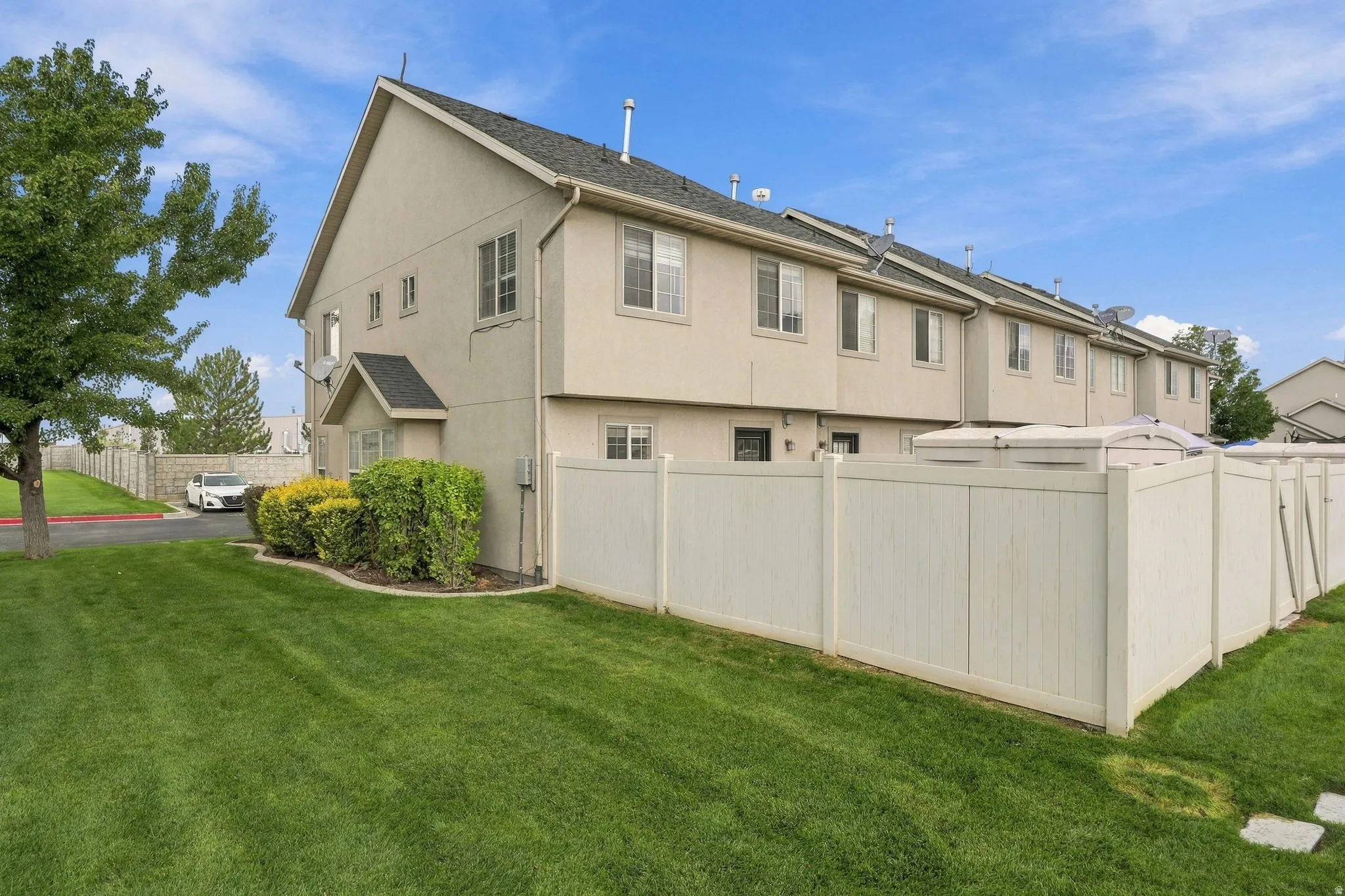Two-story stucco exterior with a gabled roofline, multiple windows, and a private vinyl fence