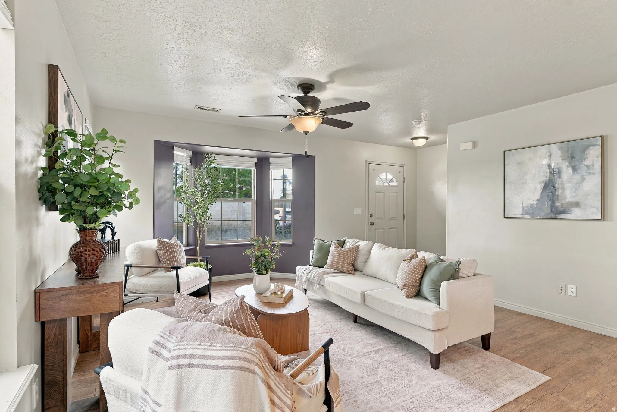 Wood-finish flooring, bay windows, ceiling fan, recessed lighting, and a white entry door with a decorative glass insert