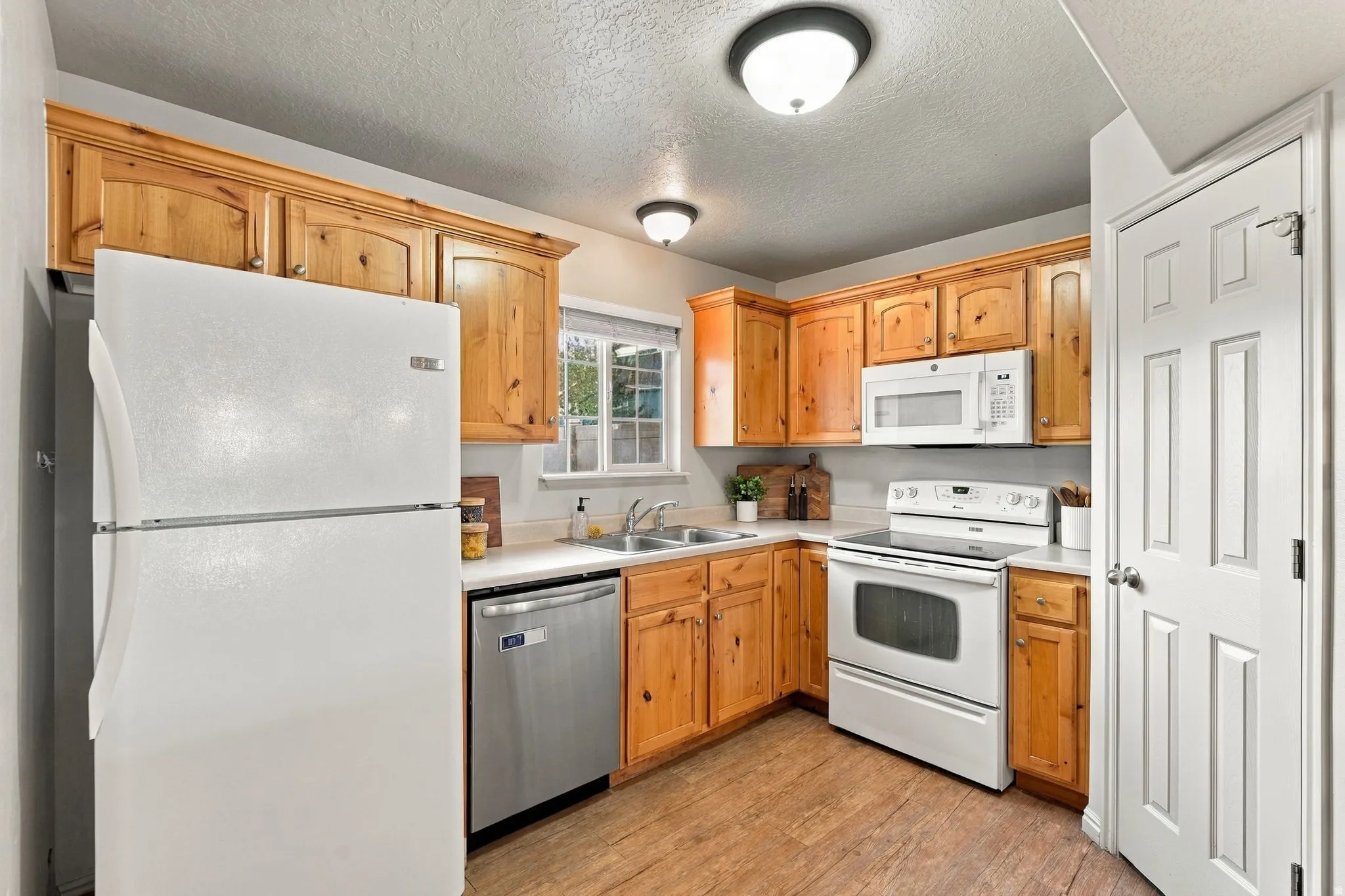 Kitchen featuring wood-finish cabinetry, light-toned countertops, and wood-finish flooring