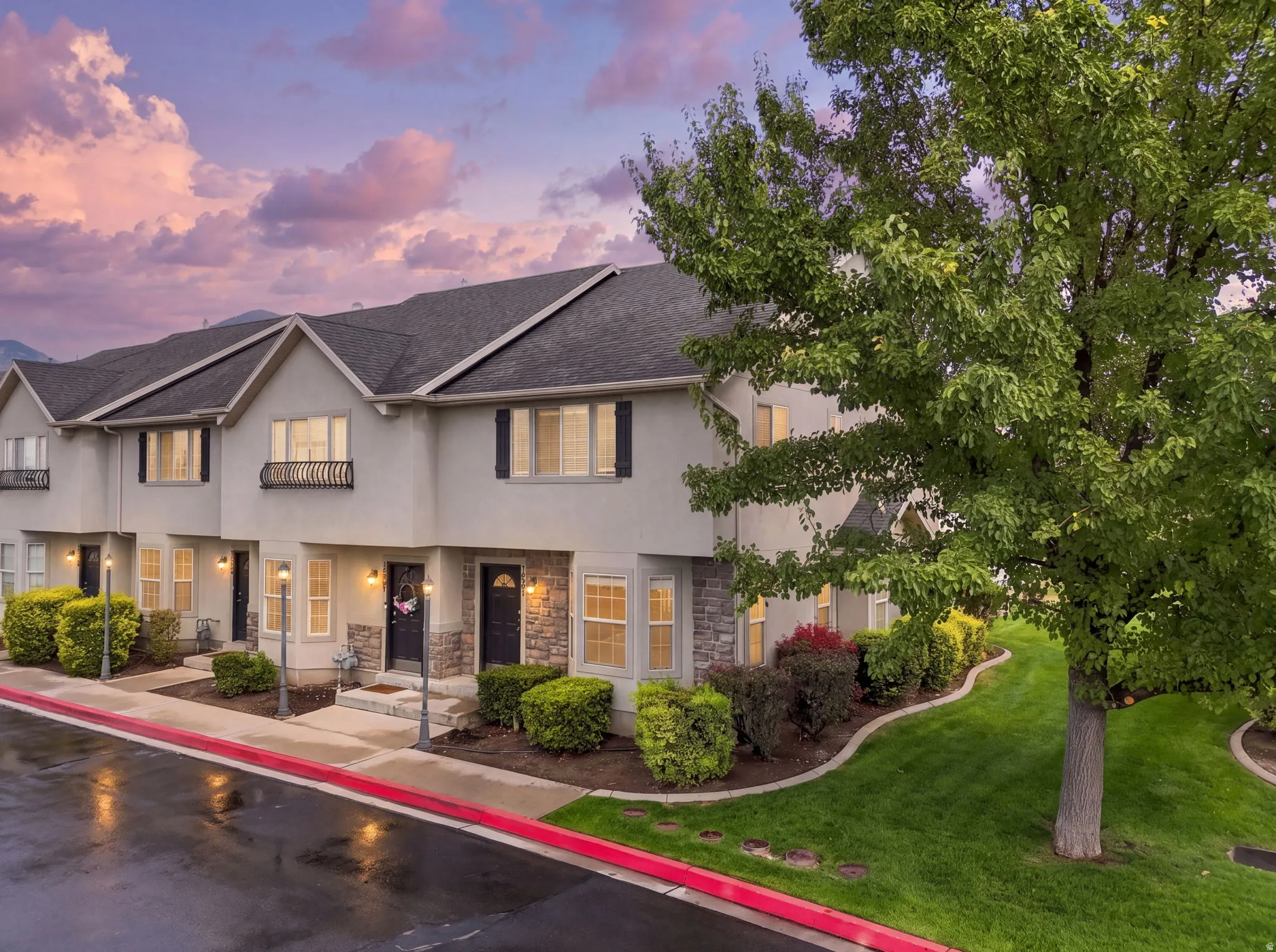 Stucco exterior with stone accents, covered entryways, mature landscaping, and a well-maintained lawn