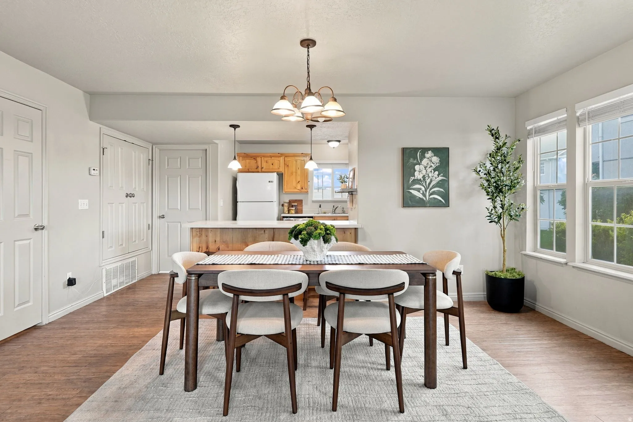 Open concept living space with a dining area, wood-finish flooring, and multiple windows