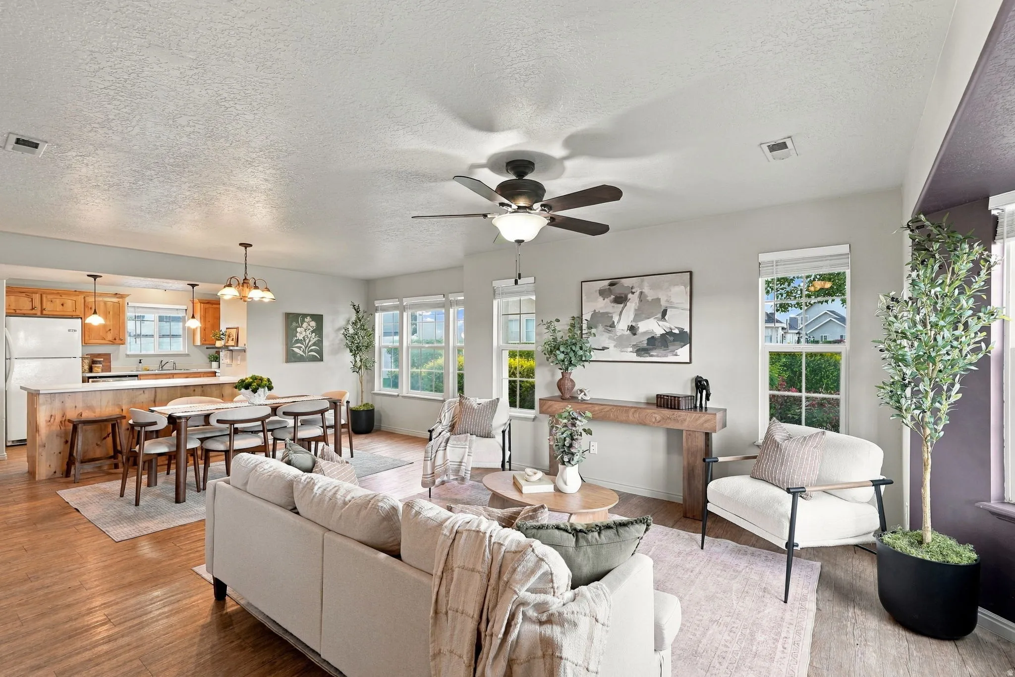 Hardwood-finish flooring throughout, bright kitchen with wood cabinetry, dedicated dining area, and multiple large windows