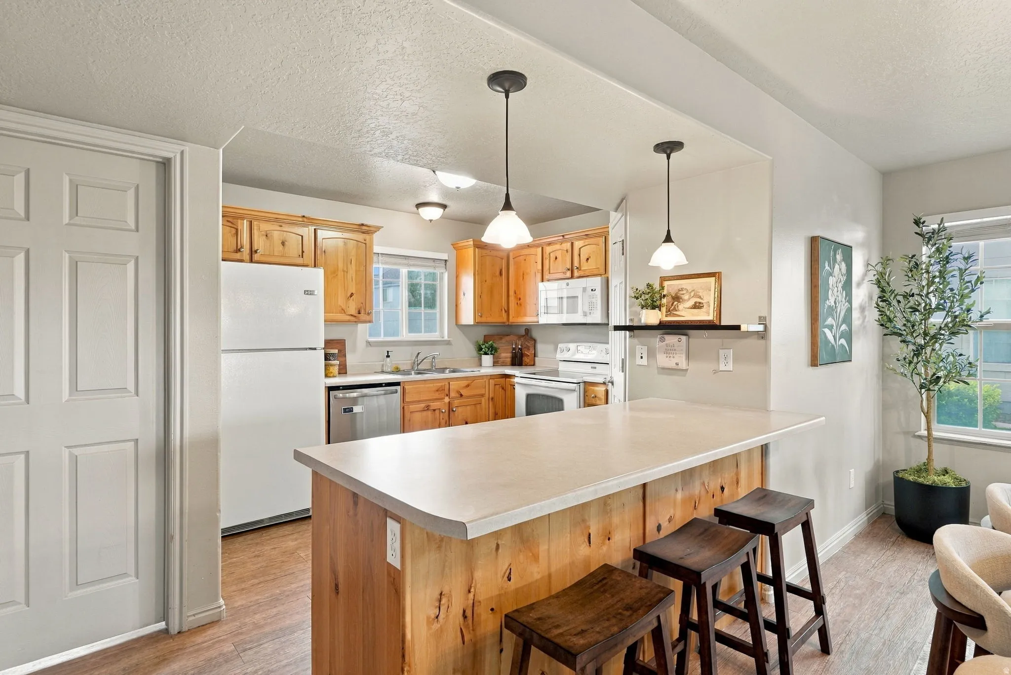 Kitchen featuring wood cabinetry, white appliances, and a central island with countertop seating